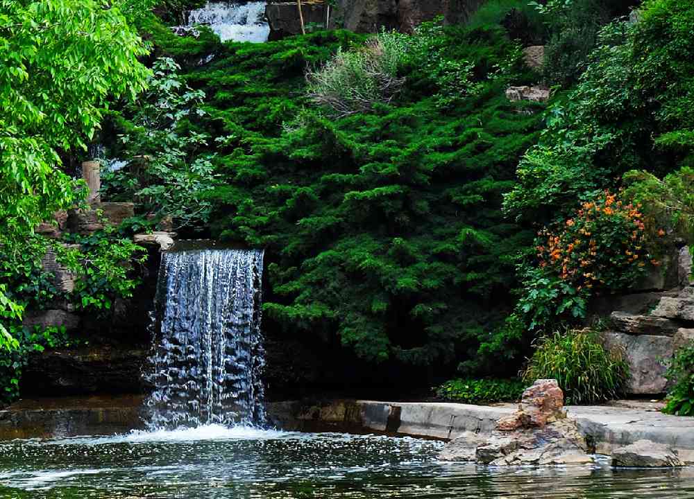 نمایی از آبشار زیبا داخل پوشش سرسبز درختی باغ گیاه شناسی ملی ایران