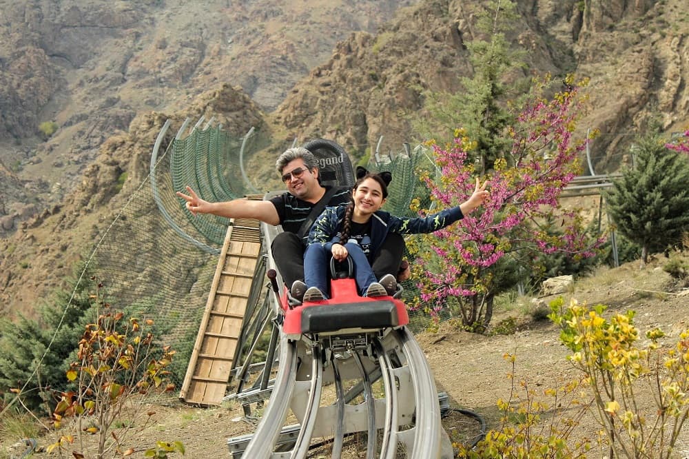نمایی از یک پدر و دختر در حال لذت بردن از سورتمهسواری در مجموعه تفریحی توچال