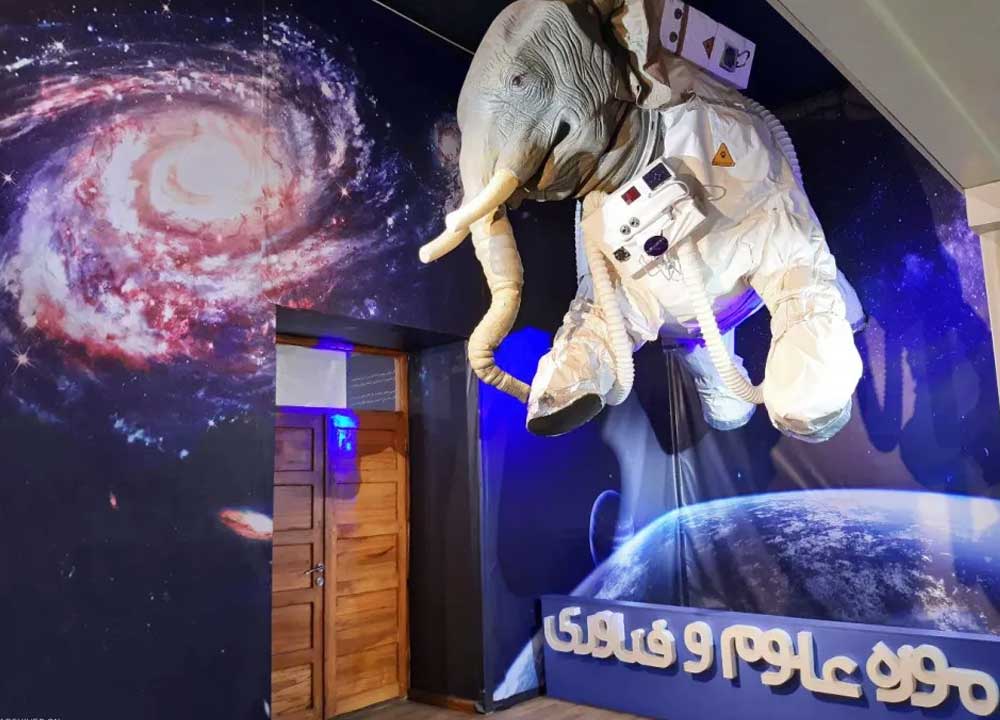 فیلی در لباس ربات آویزان شده از سقف جلوی درب موزه علوم و فناوری