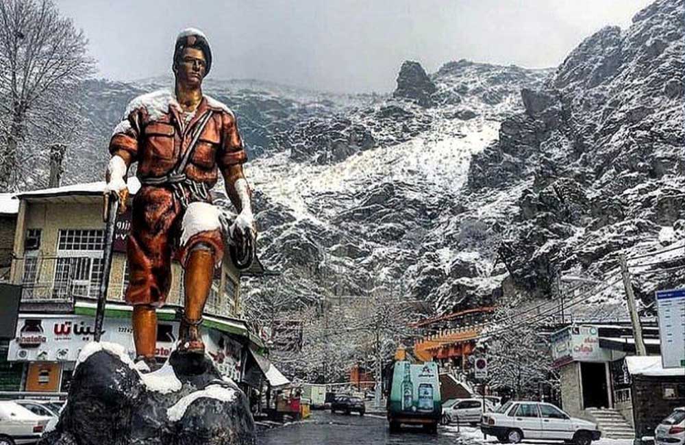 مجسمهای در میدان دربند با پسزمینه کوههای پوشیده در برف