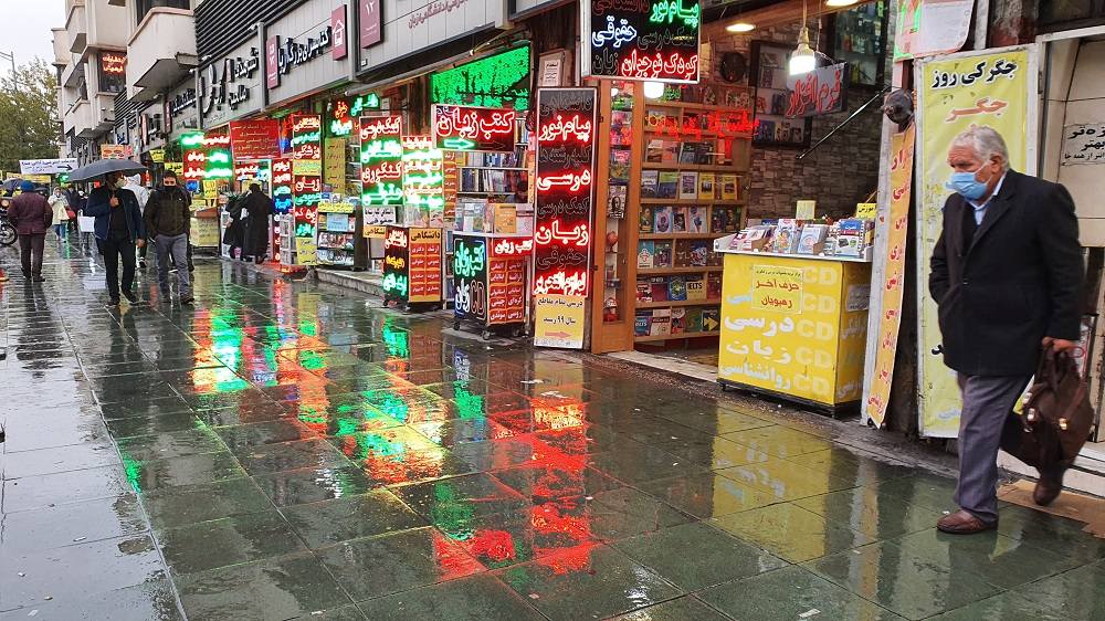 نمایی از پیاده‌روی در راسته کتاب‌فروشی‌های خیابان انقلاب تهران در یک روز بارانی