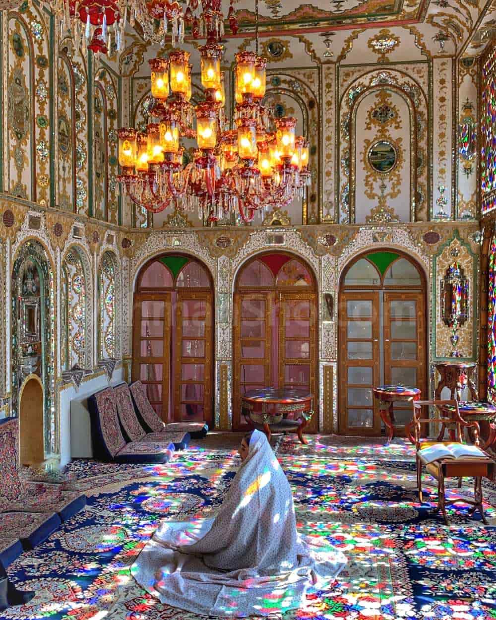یک خانم با چادر سفید که در اتاق شاه نشین خانه ملاباشی در اصفهان نشسته