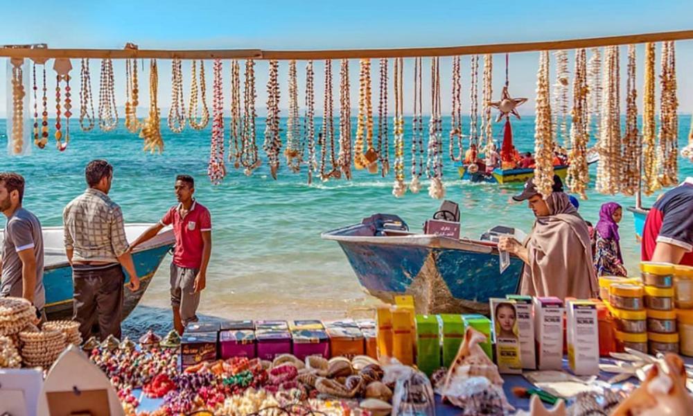 غرفه بازار محلی کنار دریای آبی و چند نفر در بک گراند