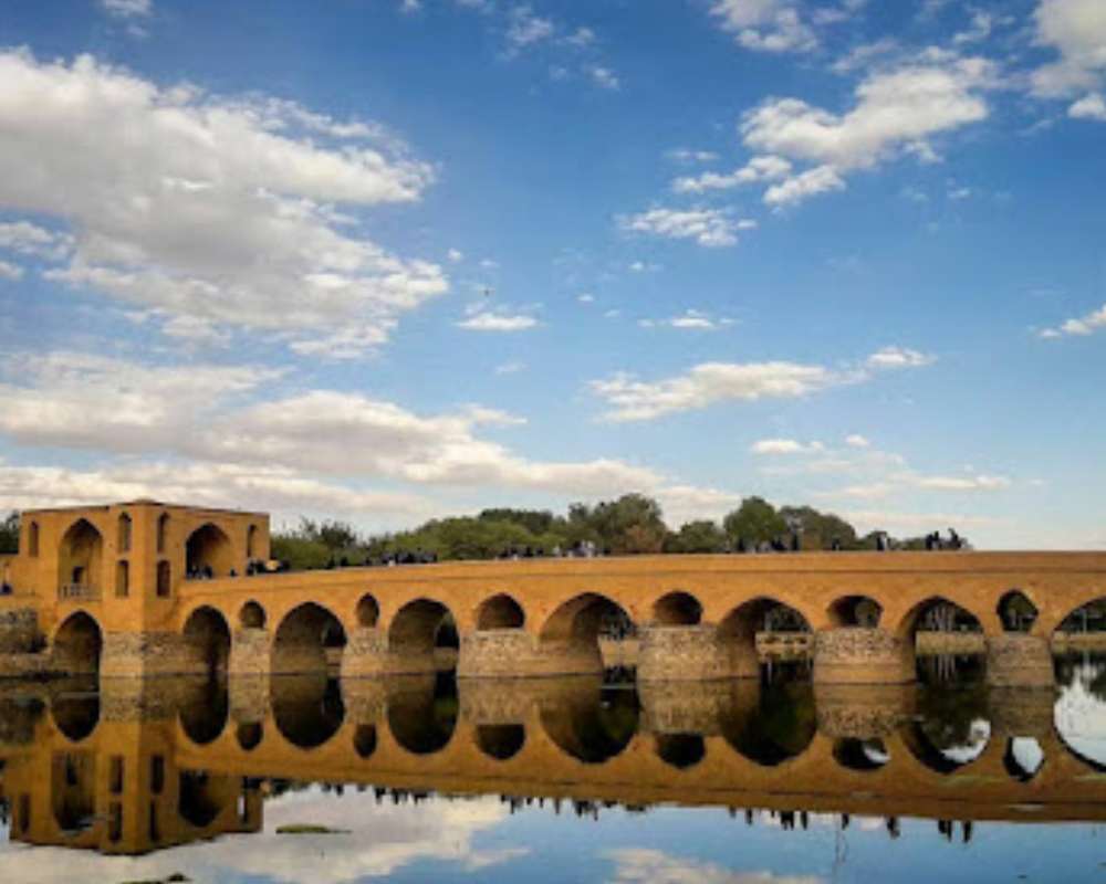 نمای پل شهرستان و تصویر آن در آب به همراه آسمان آبی