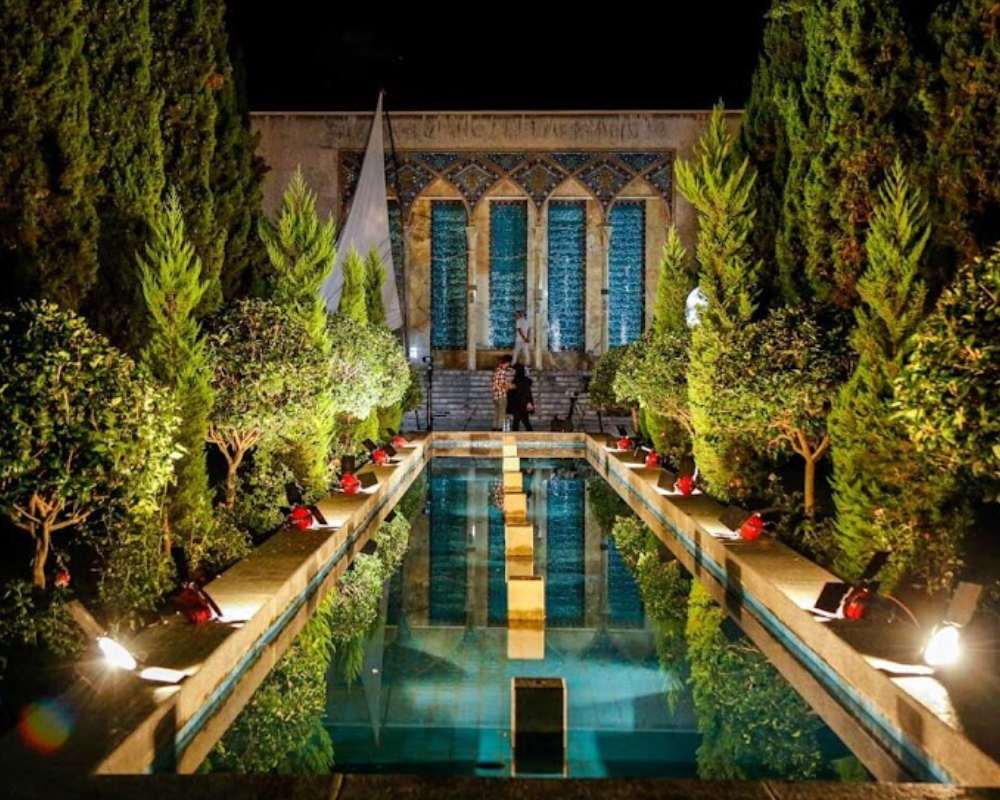 نمای محوطه آرامگاه در شب با نورپردازی بینظیر و تصاویری که بر آب حوض افتاده