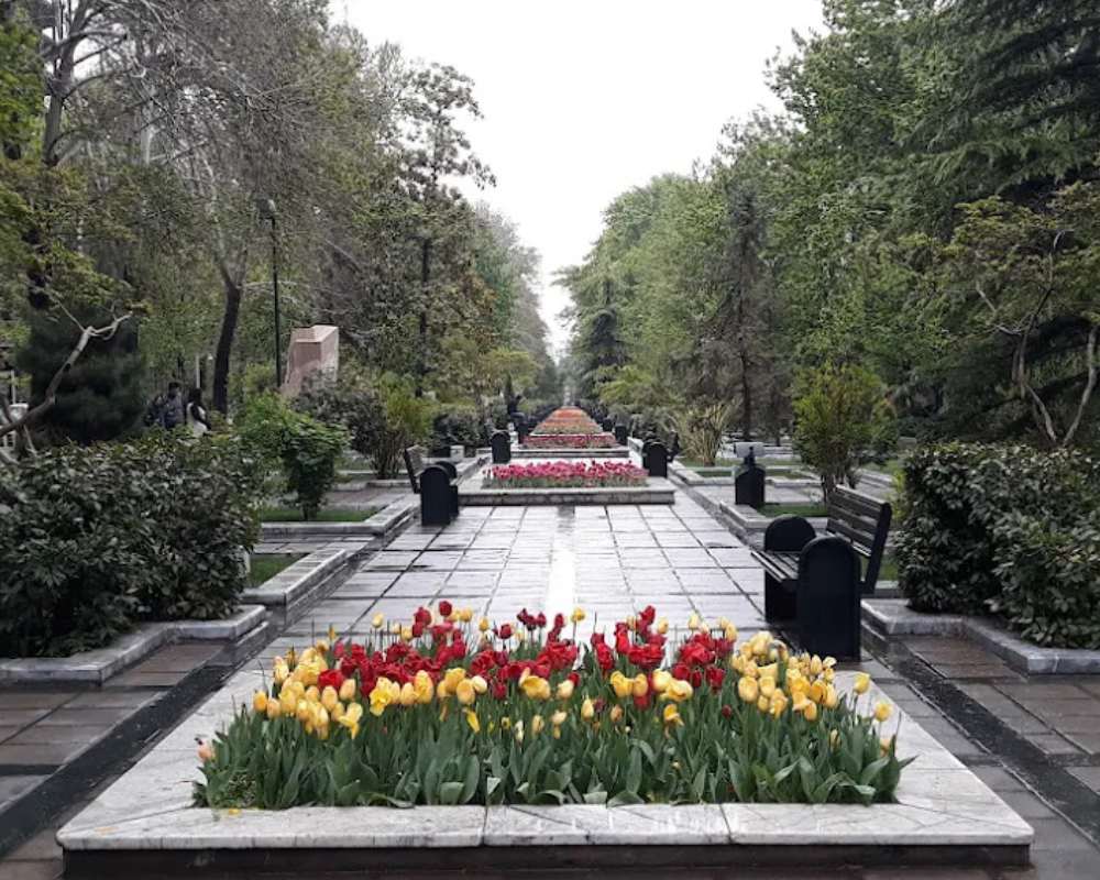 نمای روز بارانی پارک ملت و باغچه پر از گل لاله زرد و قرمز