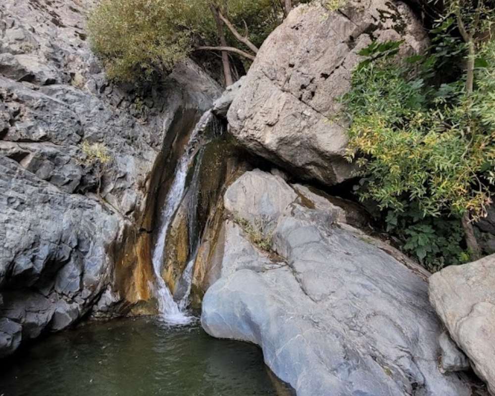 نمایی از آبشار چالمگس دارآباد در میان سنگها و درختان سبز