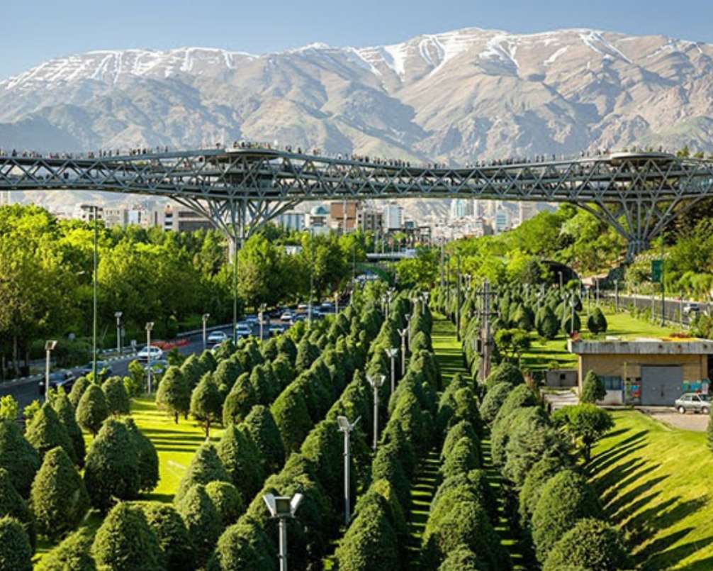 فضای سبز پارک آب و آتش و پل طبیعت در پس زمینه کوه های تهران
