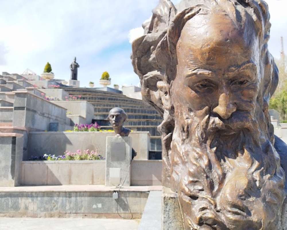 نمای نزدیک یکی از مجسمه‌ها با پس زمینه پله و چند مجسمه دیگر