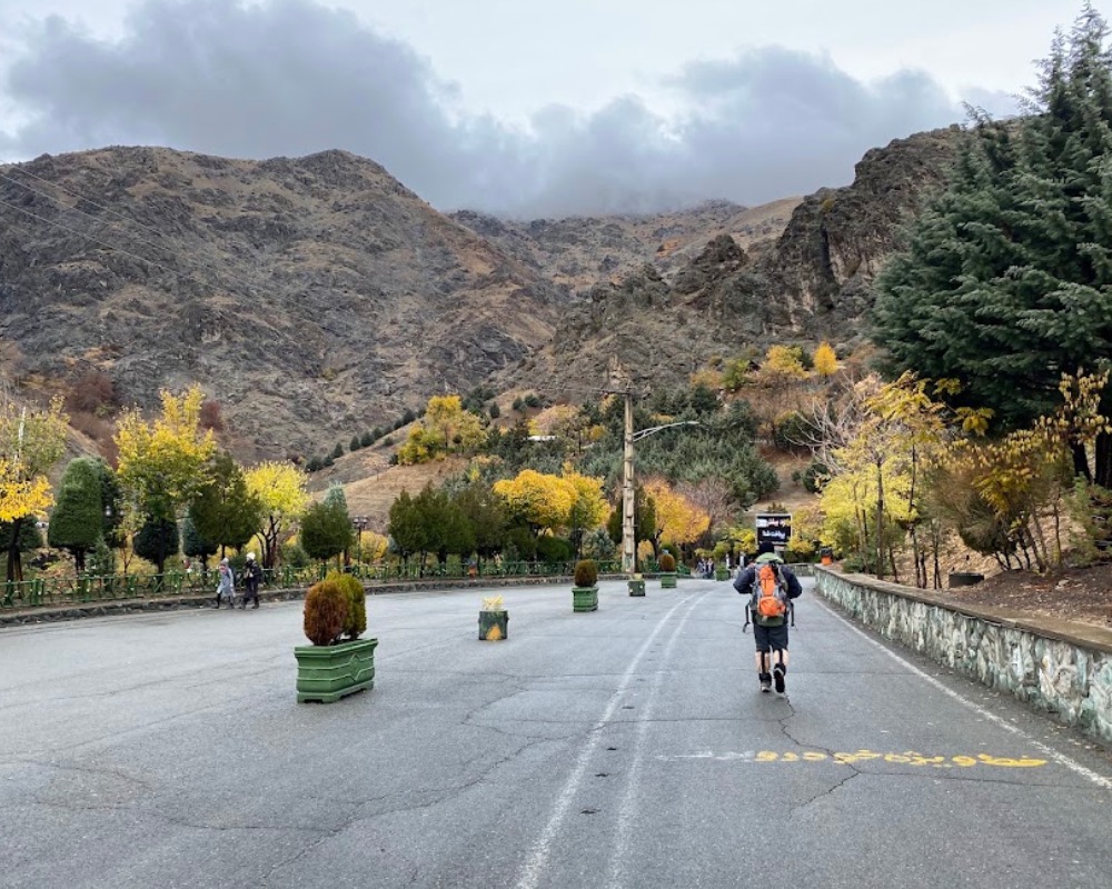 مرد کوهنوردی در حال پیاده روی در توچال در یک روز بارانی