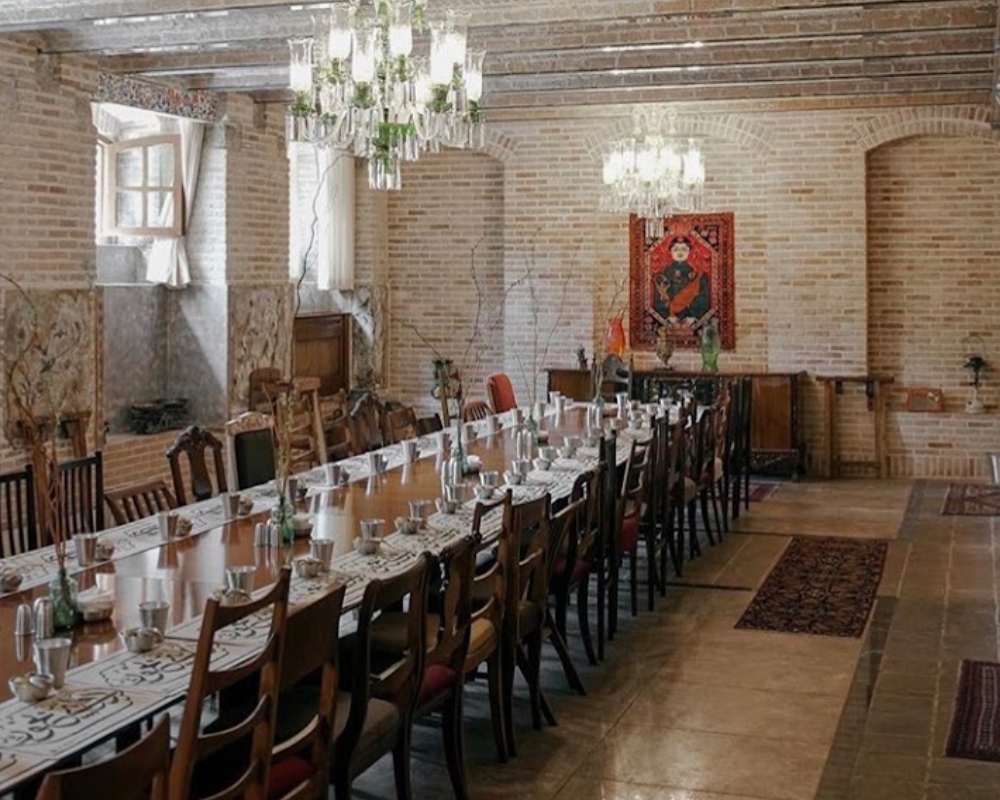 نمایی از یک میز بزرگ و صندلی‌هایش در محوطه داخلی رستوران روحی تهران