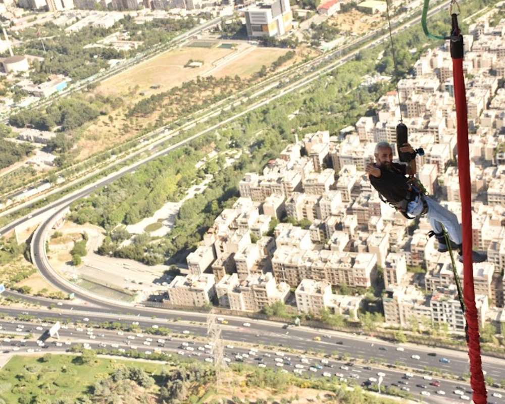 مردی با کمربند و آمادگی امنیتی در ارتفاع بالای برج میلاد برای آماده شدن پرت شدن و سقوط