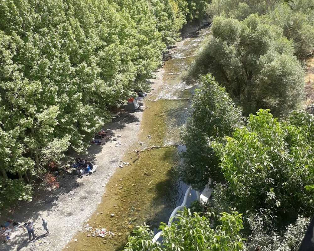 نمایی از بخش کم عمق رودخانه کردان و افرادی که بساز پیک نیک پهن کردهاند