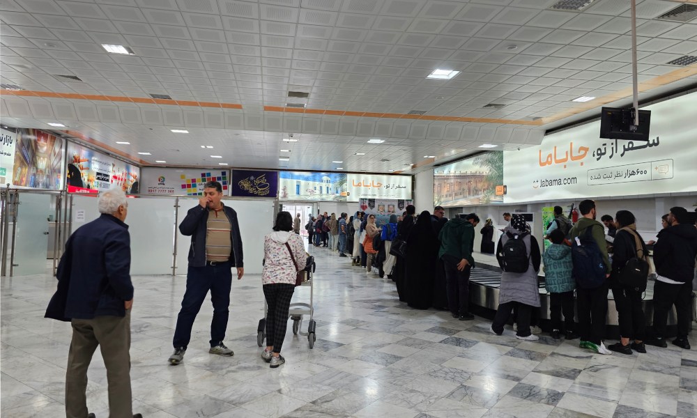 جمعیت منتظر بار چمدان در فضای داخلی فرودگاه