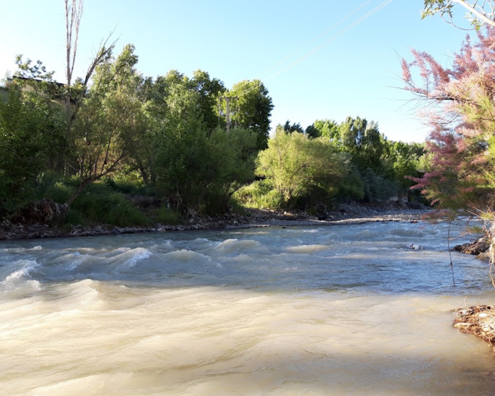 نمای نزدیک رودخانه کردان با پس زمینه درختان و آسمان آبی