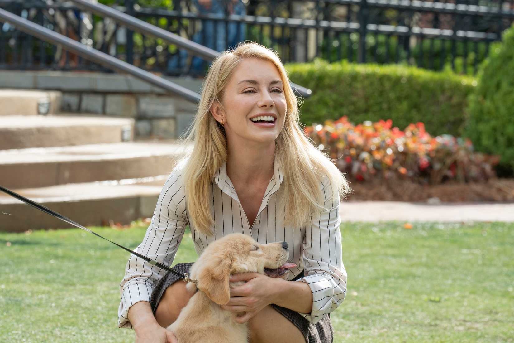 امیلیا هارکورت (جنیفر هالند) یک توله سگ را در Peacemaker در آغوش گرفته است