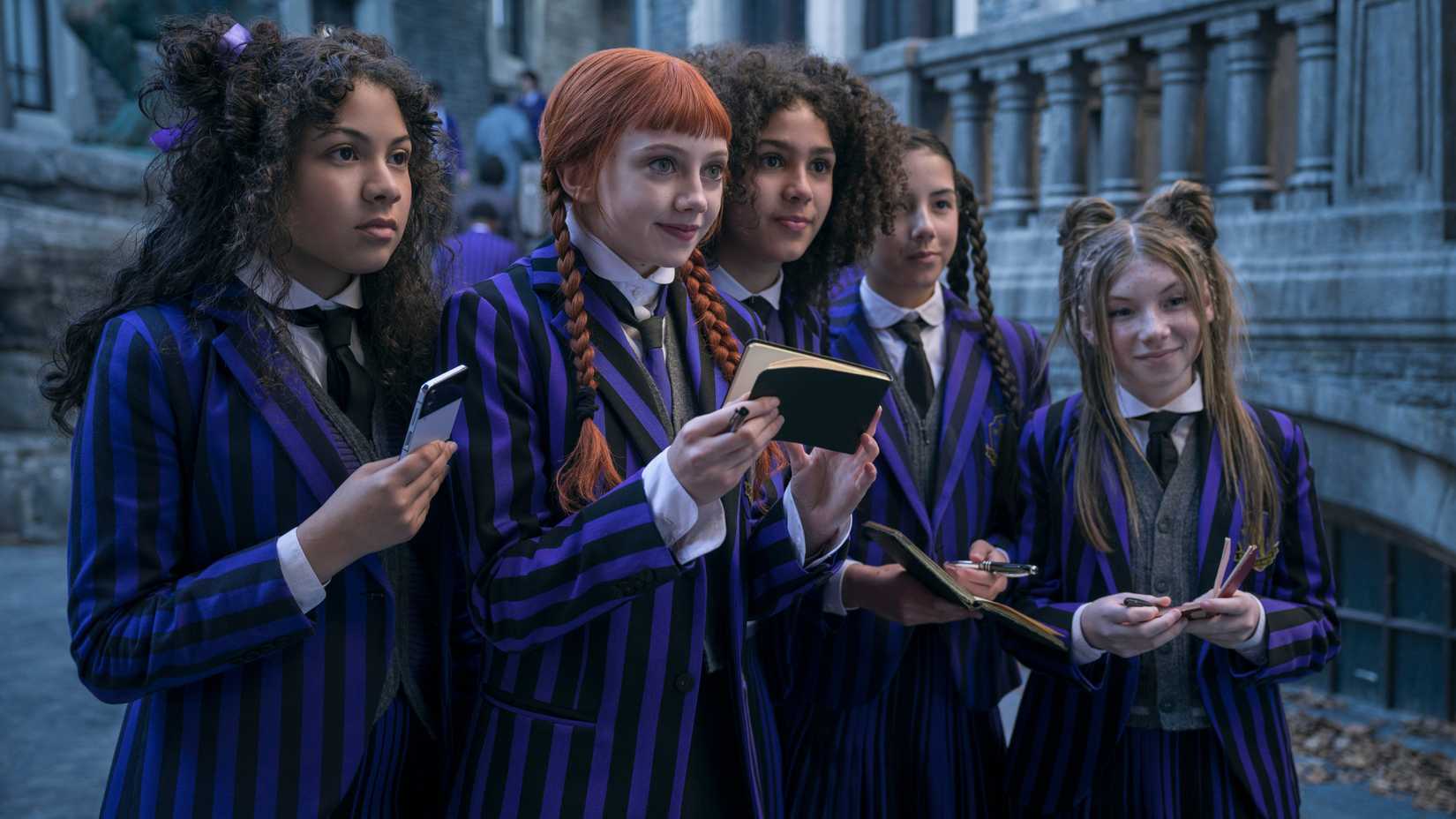 اوی تمپلتون در نقش اگنس دمیل با دیگر دانش‌آموزان نورمور که به دنبال امضا هستند در سریال Wednesday